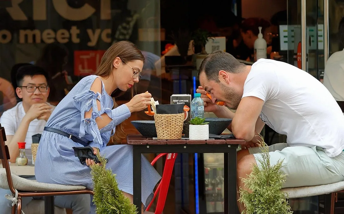 屋外テラスのレストランで食事をするカップル